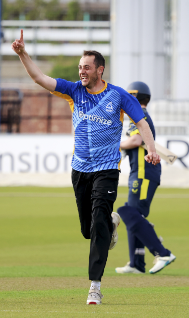 Alfie Pyle celebrates a wicket with one arm in the air