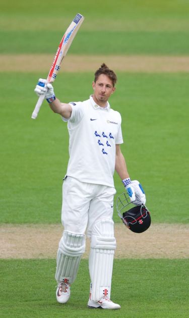 John Simpson raises his bat after reaching his century.