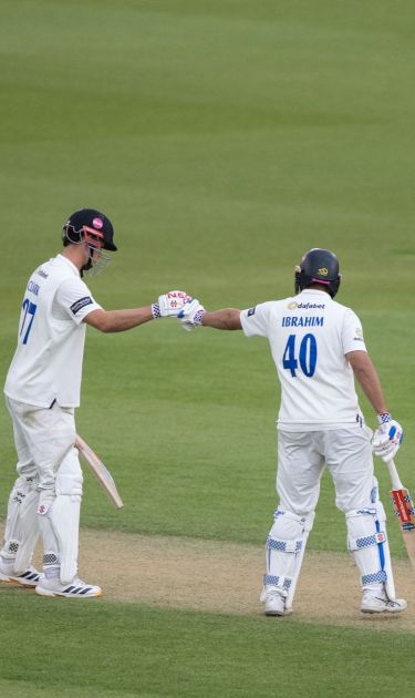 Tom Clark and Dan Ibrahim fist bump while batting together.