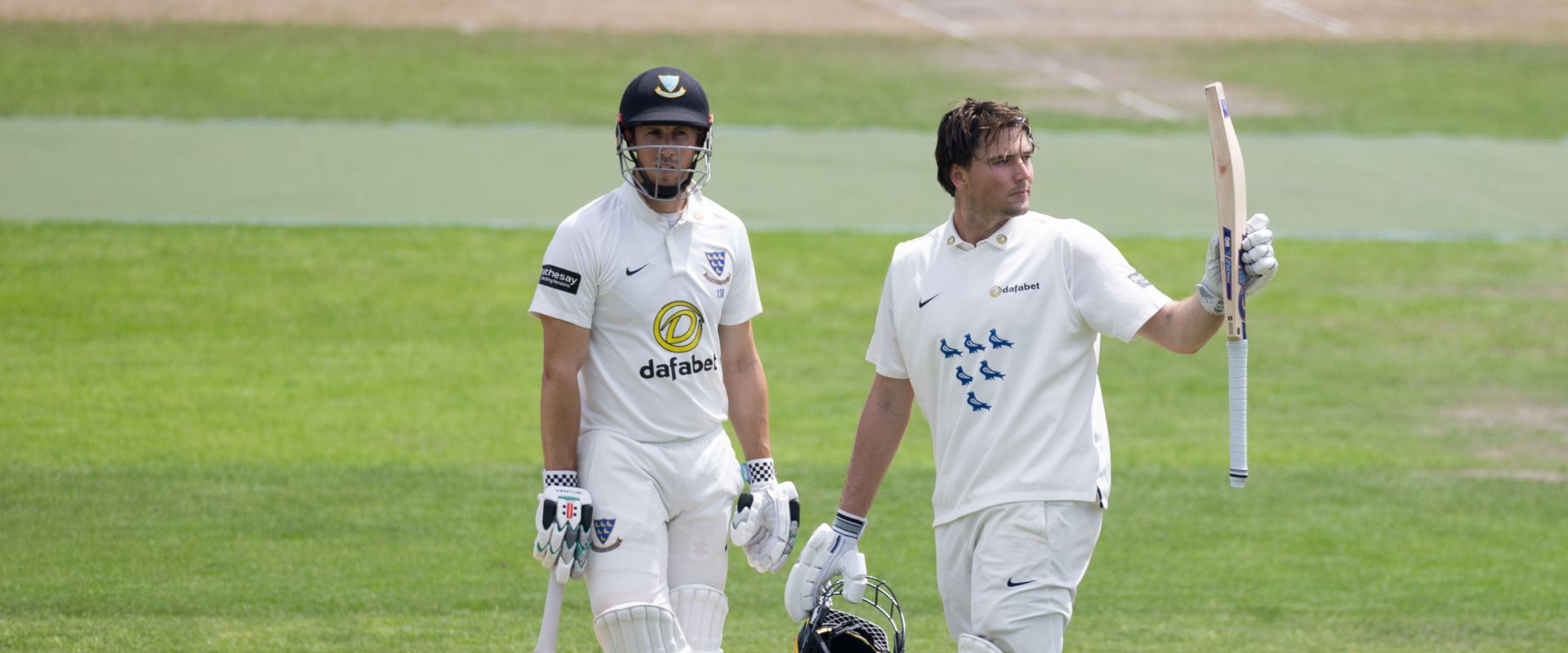 James Coles raises his bat to celebrate his century against Warwickshire.