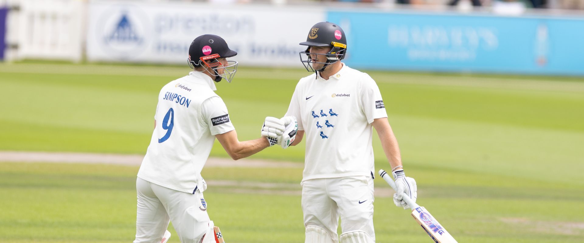 John Simpson and James Coles shake hands while batting together.