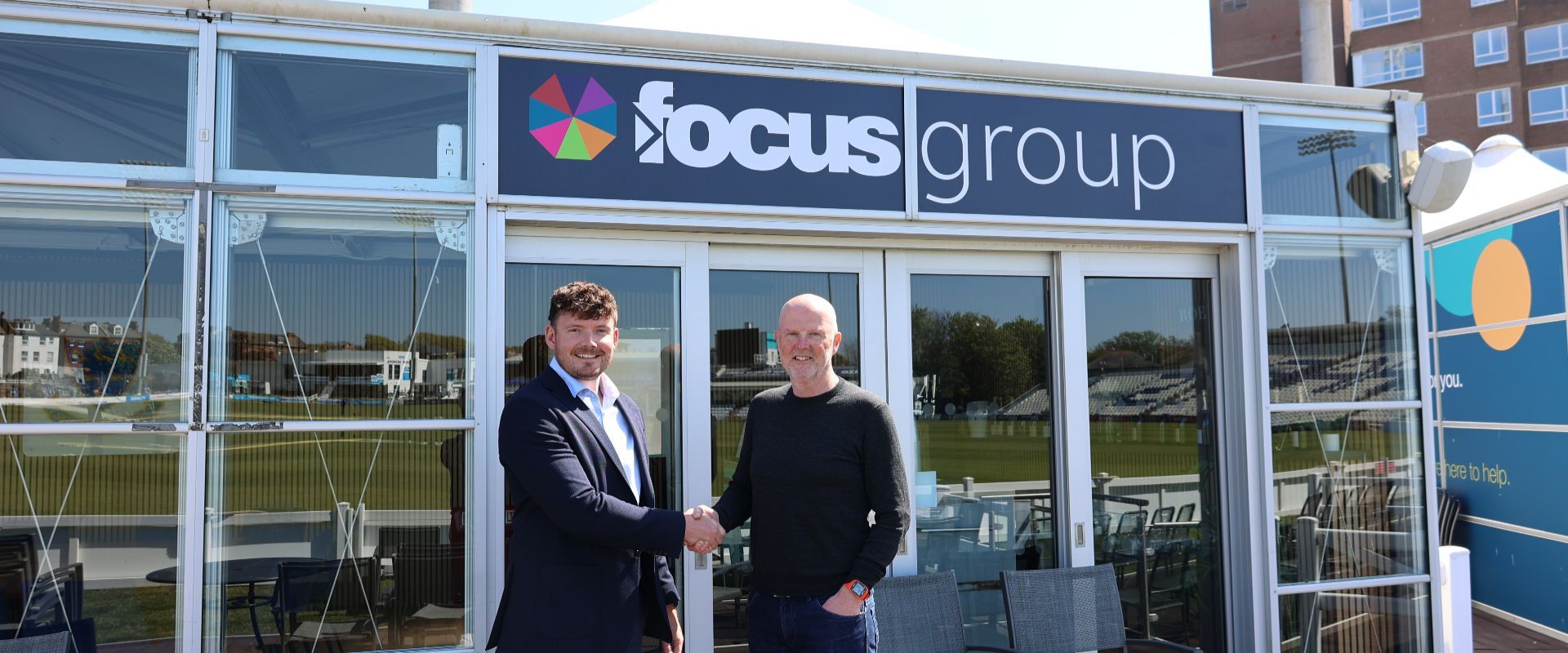 Wesley McGovern and Mark West shake hands in front of the new Focus Group Executive Lounge.