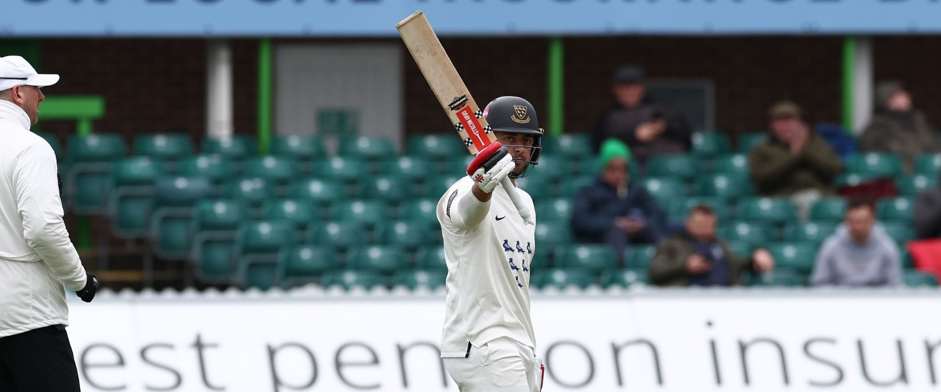 Tom Haines raises the bat as he passes 50