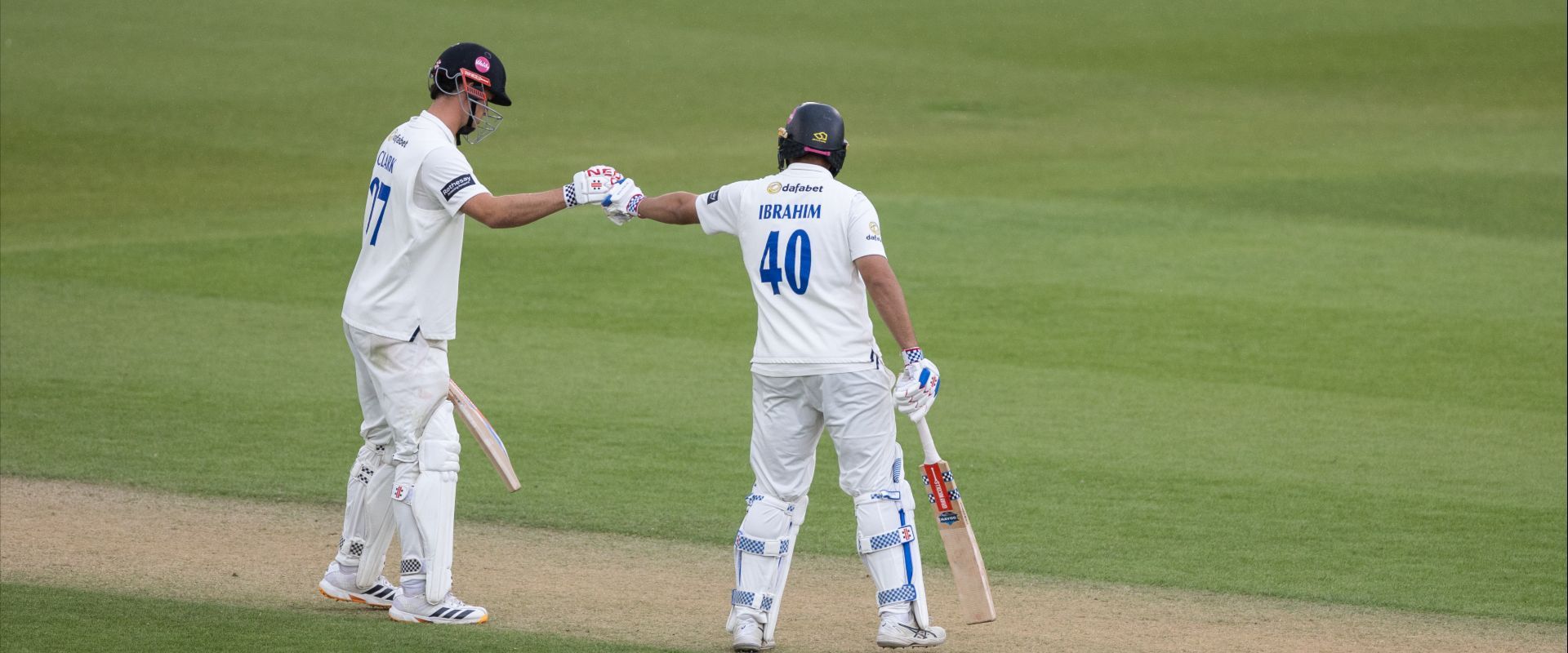 Tom Clark and Dan Ibrahim fist bump while batting together.