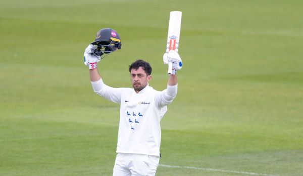 Tom Haines raises his helmet and bat to celebrate reaching his century against Somerset.