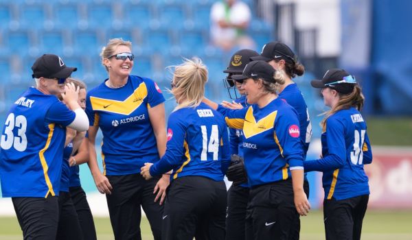 Sussex Sharks Women celebrate a wicket together.