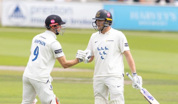 John Simpson and James Coles shake hands while batting together.