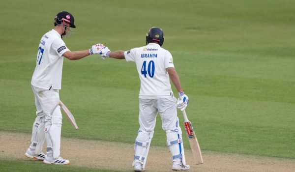 Tom Clark and Dan Ibrahim fist bump while batting together.