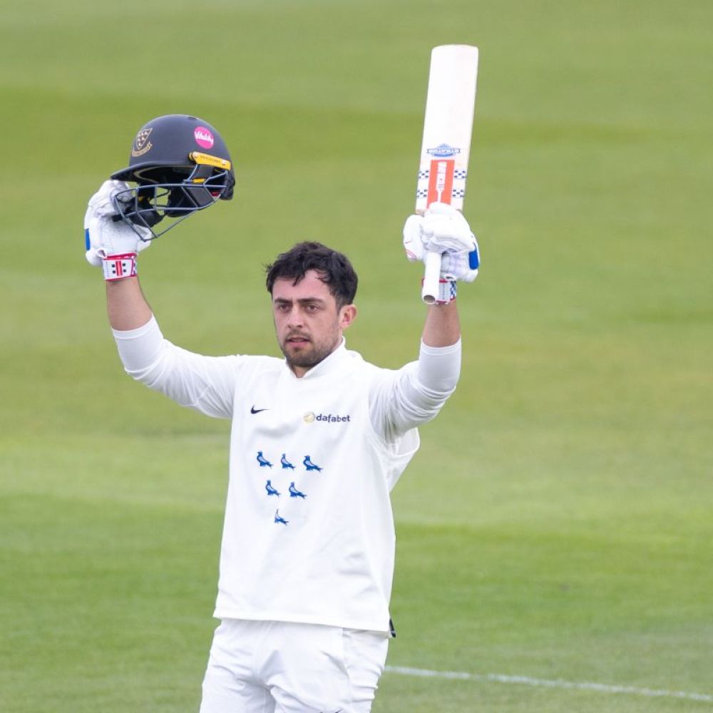 Tom Haines raises his helmet and bat to celebrate reaching his century against Somerset.